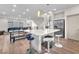Open-concept kitchen island with white countertop, dining, and living area featuring sleek barstools and modern pendant lighting at 8076 Haywood Estate Ave, Las Vegas, NV 89113