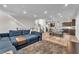 Open-concept living area featuring a large sectional sofa, wood floors, and a view of the kitchen and staircase at 8076 Haywood Estate Ave, Las Vegas, NV 89113