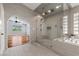 Sleek main bathroom boasts a glass shower, soaking tub, and arched doorway to bedroom at 9417 Grenville Ave, Las Vegas, NV 89134