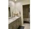 Well-lit bathroom featuring double vanity, granite countertop, and bath with tile surround at 1885 Vass Springs Pl, North Las Vegas, NV 89084