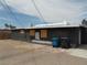 Rear exterior view of the property with boarded windows, trash receptacles and a paved area at 1912 Statz St, North Las Vegas, NV 89030