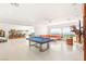 Expansive living room with a pool table, large windows, and seamless flow into a formal dining area at 20 Kittansett Loop, Henderson, NV 89052
