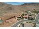 Expansive aerial view of a desert community showcases the house, land, community pool, tile roofs, and desert landscaping at 205 Red Rock Rd, Boulder City, NV 89005