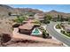 Breathtaking aerial view showcases this home nestled against desert mountainside; pool, tile roof, circular driveway and premium lot at 205 Red Rock Rd, Boulder City, NV 89005