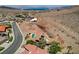 Aerial view of a desert landscape with a home that has a backyard pool and tile roof at 205 Red Rock Rd, Boulder City, NV 89005