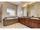 Bright bathroom with a soaking tub, glass block window, and vanity with dual sinks at 205 Red Rock Rd, Boulder City, NV 89005