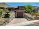 View of the house featuring a two-car garage, rock landscaping, and a terracotta tile roof at 205 Red Rock Rd, Boulder City, NV 89005