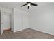 Carpeted bedroom featuring a ceiling fan, closet and a door leading to wood flooring at 2596 Lazy Saddle Dr, Henderson, NV 89002
