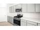 Close-up of the kitchen featuring gray cabinets, white countertops, stainless steel appliances, and wood-look floors at 336 Taylor St, Henderson, NV 89015