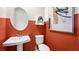 A well-lit powder room featuring modern fixtures, white porcelain, and orange accent wall at 338 Taylor St, Henderson, NV 89015