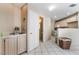 Bright kitchen with tile flooring and light wood cabinets, adjacent to a small sink and bathroom at 3950 S Sandhill Rd # 130, Las Vegas, NV 89121