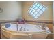 Close-up of jetted tub with tile surround and unique window for natural light at 401 Obsidian St, Las Vegas, NV 89145