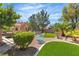 Beautifully landscaped backyard featuring artificial turf, seating areas, and mature shade trees at 4196 Balmoral Castle Ct, Las Vegas, NV 89141