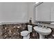 Elegant powder room with marble-style wall and a decorative tiled base plus designer mirror at 4196 Balmoral Castle Ct, Las Vegas, NV 89141