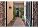 Inviting entryway showcasing a black door, stone columns, a paved walkway, and flourishing greenery at 4196 Balmoral Castle Ct, Las Vegas, NV 89141
