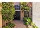 Welcoming front entryway featuring a decorative black door, trimmed plants, and a paved walkway at 4196 Balmoral Castle Ct, Las Vegas, NV 89141