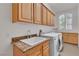 Bright laundry room features ample cabinet space, granite countertops, and a modern washer and dryer at 4196 Balmoral Castle Ct, Las Vegas, NV 89141