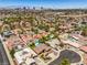 Expansive aerial view of a residential community featuring mature landscaping, swimming pools, and stunning Las Vegas skyline views at 4475 Harmony Ct, Las Vegas, NV 89121