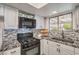 Well-lit kitchen showcasing stone backsplash, granite countertops, gas range, and a black double basin sink at 4475 Harmony Ct, Las Vegas, NV 89121
