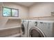 Bright laundry room area featuring a washer and dryer with functional shelving for storage at 4475 Harmony Ct, Las Vegas, NV 89121