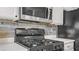 Close-up of stainless steel gas range and built-in microwave with stone backsplash at 482 Painted Sage Ct, Henderson, NV 89015
