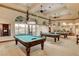 The billiard room features elegant chandeliers over the billiard tables and expansive windows for natural light at 4845 Santo Romeo St, Las Vegas, NV 89135