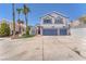 Two-story home featuring a two-car garage, a well-manicured lawn and palm trees on a sunny day at 4871 La Princesa Ct, North Las Vegas, NV 89031