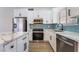 Well-equipped kitchen with stainless steel refrigerator, range, microwave, blue backsplash and marble countertops at 806 Fireweed Dr, Henderson, NV 89002