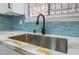 Close-up of the stainless steel kitchen sink with marble countertops and unique blue backsplash at 806 Fireweed Dr, Henderson, NV 89002