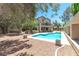 A serene backyard with a pool, gravel landscaping, and mature trees, perfect for outdoor relaxation and entertainment at 8800 Cortile Dr, Las Vegas, NV 89134