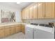 Bright laundry room with ample cabinet space, tile backsplash, and modern washer and dryer units at 8800 Cortile Dr, Las Vegas, NV 89134