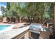 A well-equipped outdoor kitchen and barbecue area adjacent to the pool with mature shade trees and ample counter space at 8800 Cortile Dr, Las Vegas, NV 89134