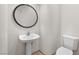 Compact powder room with pedestal sink, modern faucet, round mirror, and water-efficient toilet at 8800 Cortile Dr, Las Vegas, NV 89134