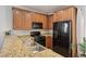 Efficient kitchen features wood cabinetry, granite counters, and black appliances at 9053 Entrancing Ave, Las Vegas, NV 89149