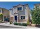 View of a two-story tan stucco house with a blue front door and well-maintained landscaping at 9140 Entrancing Ave, Las Vegas, NV 89149