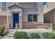 A cozy front porch with a beige railing and trimmed green bushes leading to a vibrant blue front door at 9140 Entrancing Ave, Las Vegas, NV 89149
