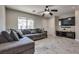 Living room with gray tile flooring, a sectional sofa, a ceiling fan, and a wall-mounted TV at 9140 Entrancing Ave, Las Vegas, NV 89149