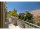 This balcony features a white railing, stone pillars, and a view of lush trees and neighboring rooftops against a blue sky at 939 Paisley St, Las Vegas, NV 89145