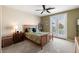 Comfortable bedroom with a ceiling fan, carpeted floors, and a bed with a wooden frame, all illuminated by a bedside lamp at 939 Paisley St, Las Vegas, NV 89145