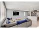 Open-concept living room featuring modern gray sofa, large TV, and access to the kitchen at 9886 Alpine Style Dr, Las Vegas, NV 89166