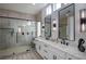 Modern bathroom with a glass-enclosed shower, double vanity with marble countertops, and contemporary lighting fixtures at 10025 Netherton Dr, Las Vegas, NV 89134