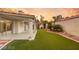 Manicured backyard with artificial turf, desert landscaping, and covered patio with a sunset backdrop at 1613 Shadow Rock Dr, Las Vegas, NV 89117