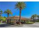 Community entrance featuring a covered drop-off area and lush landscaping with mature palm trees, and security gate at 2050 W Warm Springs Rd # 4322, Henderson, NV 89014