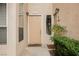 Close-up of unit 4322 front door, set in a stucco wall with decorative sconces, window and landscaped plants at 2050 W Warm Springs Rd # 4322, Henderson, NV 89014