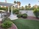 Landscaped backyard featuring a sparkling pool, covered patio, lush greenery, brick privacy wall, and plenty of room to relax at 2440 Ping Dr, Henderson, NV 89074