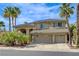 Stunning two-story home featuring a tile roof, three-car garage, and desert landscaping with palm trees at 2440 Ping Dr, Henderson, NV 89074