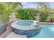 Close-up of a gorgeous tiled spa with a stone trim surround and lush landscaping at 2440 Ping Dr, Henderson, NV 89074