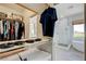 Bright walk-in closet with clothing racks and a built-in shelf, leading to a bathroom with a glass-door shower at 2440 Ping Dr, Henderson, NV 89074