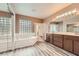 This bathroom features a soaking tub, shower, brown cabinets, and glass block window at 2784 Cherrydale Falls Dr, Henderson, NV 89052