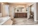 This bathroom features a soaking tub, shower, brown cabinets, and gray wood-look floors at 2784 Cherrydale Falls Dr, Henderson, NV 89052